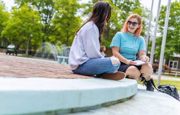 两名女学生正坐在韦伯中心前的台阶上聊天